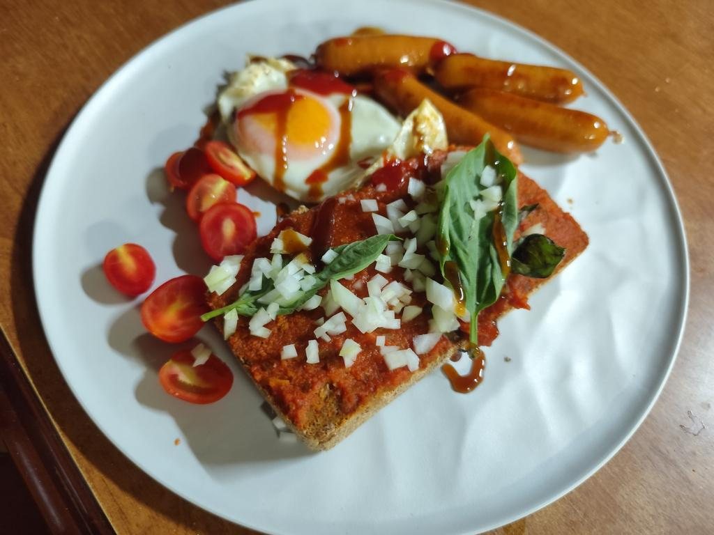 Breakfast plate: eggs, sausages, tomatoes, and toast with tomato and basil