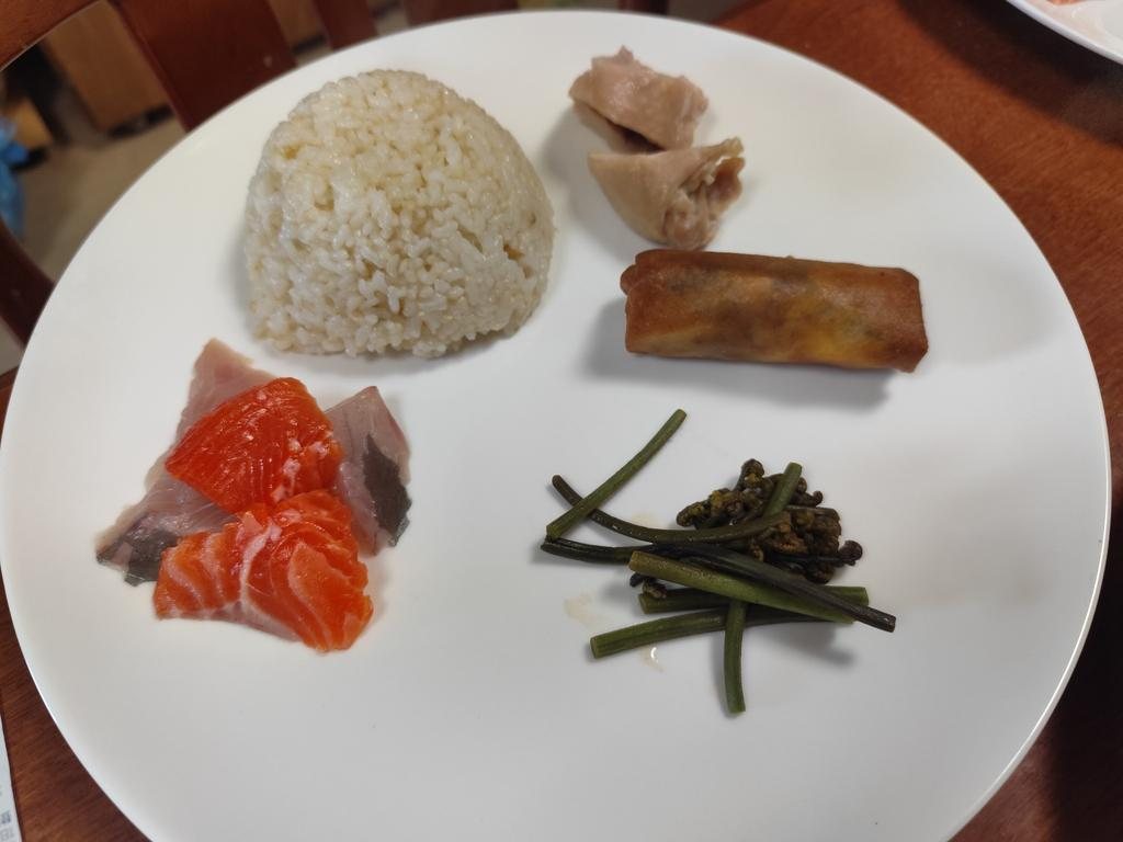 Rice, salmon, spring roll, and mountain vegetables on a white plate
