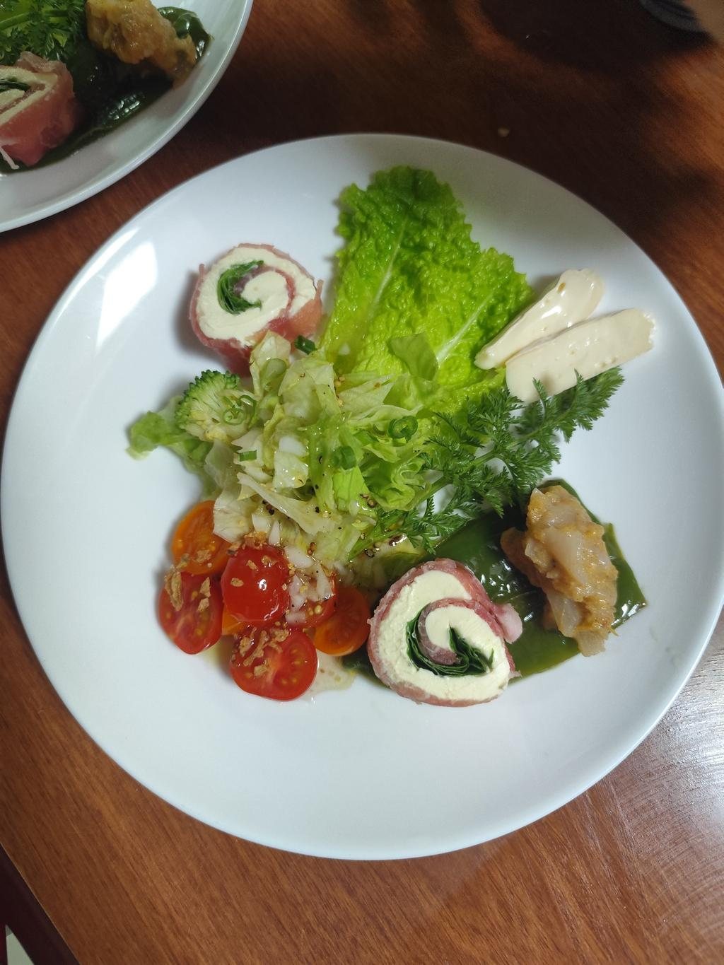 Starter of ham and cheese rolls, salad, tomatoes and herbs