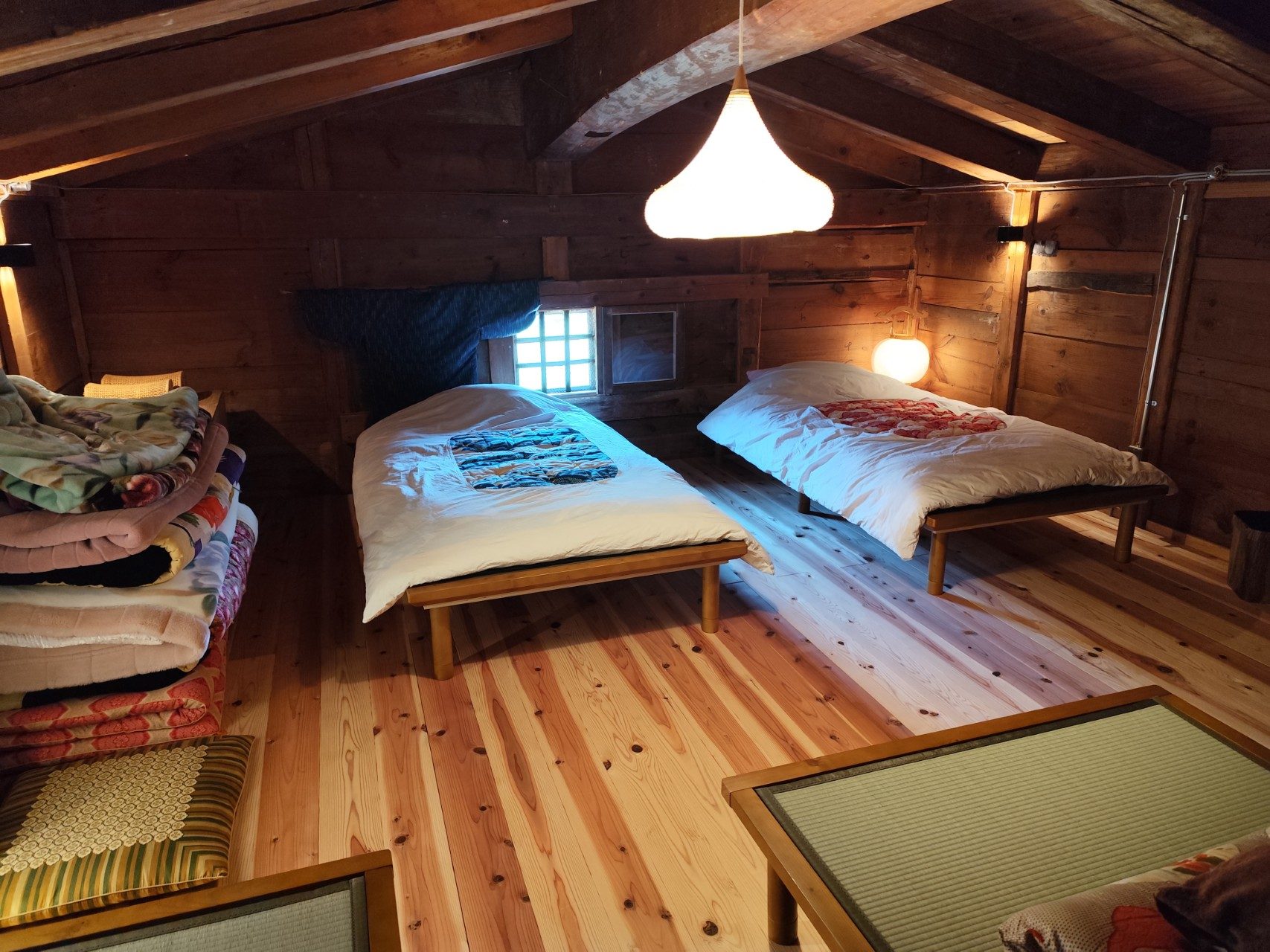 Wide view of the upstairs loft with made beds and stacked futons